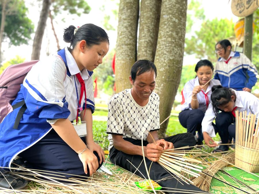 Học sinh học cách đan gùi với nghệ nhân Bahnar tại chương trình “Ngày hội Di sản văn hóa” năm 2024. Ảnh: Lam Nguyên 8571cca001ec8db2d4fd.jpg